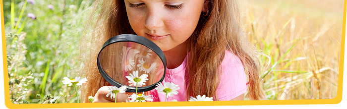 Girl studying flowers through magnifying glass